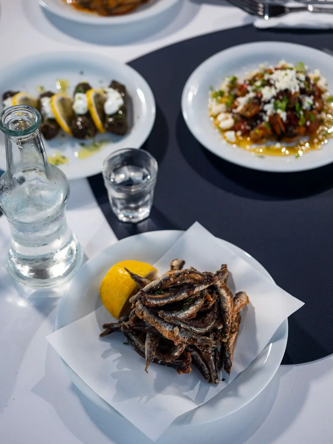 Fried marides with lemon, dolmades and mussels saganaki on a table